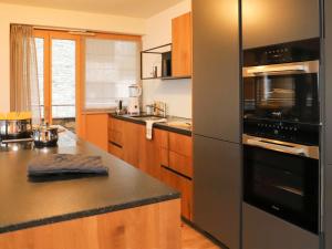 a kitchen with a black refrigerator and wooden cabinets at Apartment Hédonia A7 by Interhome in Villars-sur-Ollon