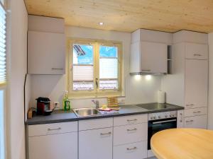 - une cuisine avec des placards blancs, un évier et une table dans l'établissement Holiday Home Chalet Dori by Interhome, à Interlaken