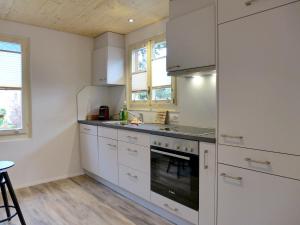 a kitchen with white cabinets and a stove top oven at Holiday Home Chalet Dori by Interhome in Interlaken