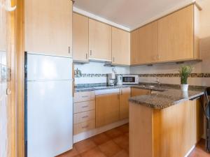 cocina con armarios de madera y nevera blanca en Apartment Stella Maris-2 by Interhome, en Roses