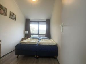 Un dormitorio con una cama en una habitación con ventana. en Wijk de Brabander 117, en Cadzand