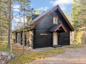 una capanna nera nel bosco con una porta bianca di Holiday Home Leviitta by Interhome a Sirkka