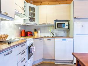 una cocina con electrodomésticos blancos y armarios de madera en Holiday Home Tulikettu 1 by Interhome, en Pyhätunturi