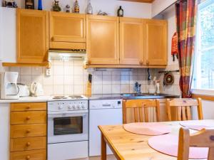 una cocina con armarios de madera y una mesa con comedor. en Holiday Home Oivanpyhä c 10 by Interhome en Pyhätunturi