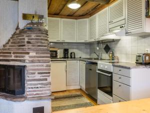 a kitchen with white cabinets and a stone fireplace at Holiday Home Luppokero 2 by Interhome in Pyhätunturi