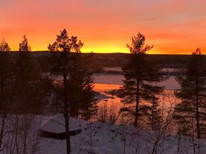 een zonsondergang boven een meer met een boot in de sneeuw bij Holiday Home Torvokoski by Interhome in Karigasniemi