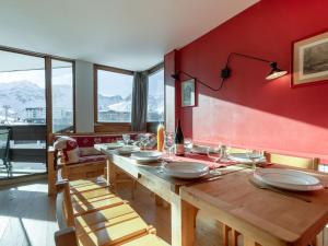 a dining room with a wooden table and red wall at Apartment Les Roches Rouges - Lavachet by Interhome in Tignes +13 photos