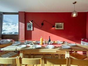 ein Esszimmer mit einem Holztisch und einer roten Wand in der Unterkunft Apartment Les Roches Rouges by Interhome in Tignes