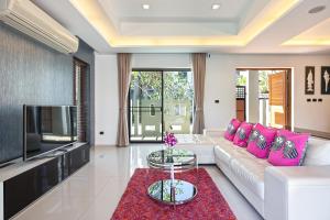 Villa Piyada في تشالونج: غرفة معيشة مع أريكة بيضاء ووسائد وردية