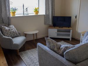 a living room with two chairs and a television at Apartment Flat 2 Keeper's Cottage by Interhome in Stenscholl