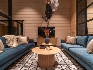 ein Wohnzimmer mit zwei blauen Sofas und einem Tisch in der Unterkunft Holiday Home Villa uggo 4 skipasses included 2024-25 by Interhome in Hyrynsalmi + 33 Fotos