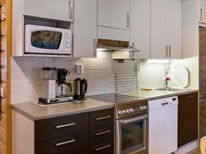a kitchen with white cabinets and a microwave at Holiday Home Kirnutie 3 by Interhome in Pyhätunturi +10 photos