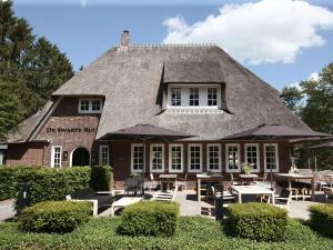 a building with tables and umbrellas in front of it at De Swarte Ruijter in Holten
