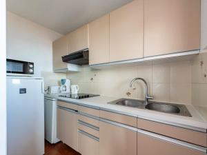 eine Küche mit weißen Schränken, einer Spüle und einem Kühlschrank in der Unterkunft Apartment Le Palazzo del Mar-12 by Interhome in Cavalaire-sur-Mer