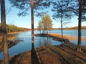 vistas a un lago con árboles y un banco en Holiday Home Jolmalompolo by Interhome en Raanujärvi