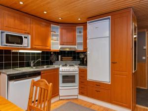 een keuken met houten kasten en een witte koelkast bij Holiday Home Antura a by Interhome in Pyhätunturi