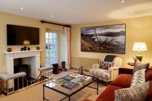 a living room with a fireplace and a tv at ALTIDO Lathallan Mill Farmhouse in Fife