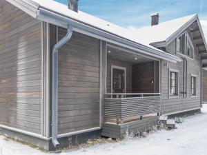 uma casa de madeira com um alpendre na neve em Holiday Home Pyhänkarhu 3 by Interhome em Pyhätunturi
