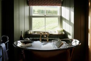 a bath tub in a bathroom with a window at ALTIDO Lathallan Mill Farmhouse in Fife