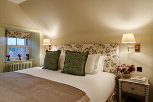 a bedroom with a large white bed with green pillows at ALTIDO Lathallan Mill Farmhouse in Fife