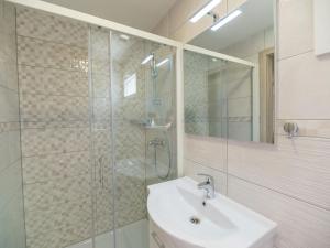 een badkamer met een wastafel en een glazen douche bij Holiday Home Seaside mobile home by Interhome in Šilo