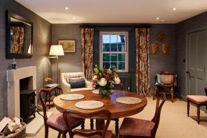 a living room with a table and chairs and a fireplace at ALTIDO Lathallan Mill Farmhouse in Fife