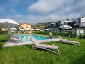a pool with chairs and umbrellas in the grass at Apartment Ormeasco by Interhome in Imperia