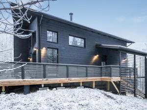 une maison noire avec une terrasse dans la neige dans l'établissement Holiday Home Villa arcus b includes 2 lift 2024-2025 by Interhome, à Pyhätunturi
