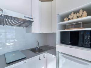 uma cozinha branca com um micro-ondas e um lavatório em Studio Les Pistes - Lavachet-4 by Interhome em Tignes