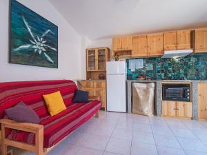 a living room with a red couch and a kitchen at Apartment Blue House by Interhome in La Caletta