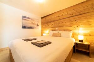 1 dormitorio con 1 cama blanca grande y pared de madera en Cozzy appart dans chalet vue Mont-Blanc 2 chambres en Megève