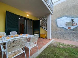 a table and chairs on a patio with a painting on the wall at Apartment Green House by Interhome in La Caletta
