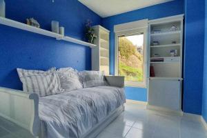 a blue bedroom with a bed and a window at Elegante Apartamento con Vistas al Mar in Suances