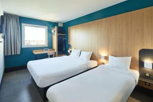 2 letti in una camera d'albergo con pareti blu di B&B HOTEL Orly Chevilly-Larue - Nationale 7 a Chevilly-Larue