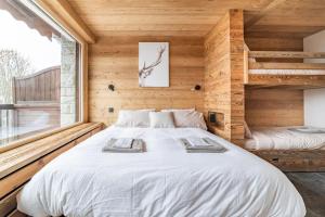a bedroom with a large white bed in a wooden wall at Cocon au pied des pistes de ski du Mont-d'Arbois in Megève