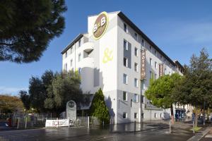 un bâtiment blanc avec un panneau sur son côté dans l'établissement B&B HOTEL Orly Chevilly-Larue - Nationale 7, à Chevilly-Larue