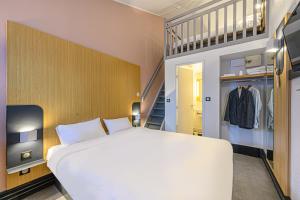 Un dormitorio con una gran cama blanca y una escalera en B&B HOTEL Vannes Est Golfe du Morbihan, en Vannes