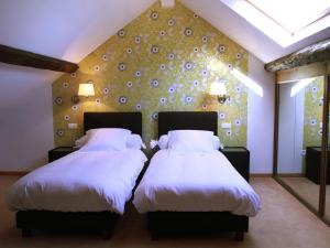a bedroom with two beds with white sheets and a wall at Hôtel - Ferme du Château d'Ahin in Huy