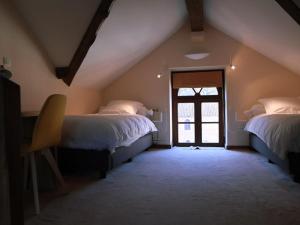 a attic room with two beds and a window at Hôtel - Ferme du Château d'Ahin in Huy