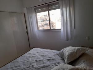1 cama no hecha en un dormitorio con ventana en Departamento reciclado a nuevo a 3 cuadras del mar en Mar del Plata