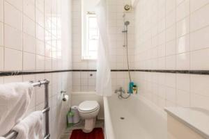 a white bathroom with a toilet and a bath tub at Great Mayfair London Flat in London
