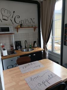 una cucina con un tavolo con due cartelli sopra di Le Samwest ad Arromanches-les-Bains