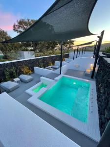 a swimming pool on a patio with an umbrella at Santa Irina Luxury Sunny Lofts in Perivolos
