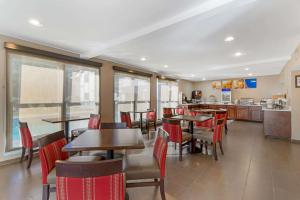 un restaurante con mesas y sillas y una cocina en Comfort Inn & Suites - near Robins Air Force Base Main Gate, en Warner Robins