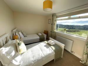 a bedroom with two beds and a large window at Pass the Keys Beautiful 5BR Rural Cottage with Outstanding Views in Castle Douglas