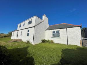 a white brick house on a grassy field at Pass the Keys Beautiful 5BR Rural Cottage with Outstanding Views in Castle Douglas