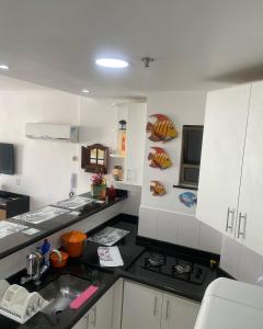 una cucina con armadi bianchi e piano di lavoro nero di Loft Prainha ad Arraial do Cabo