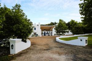 une grande maison blanche avec une allée. dans l'établissement San Gabriel Homestead, à Somerset West