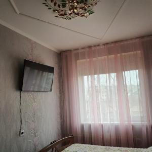 a bedroom with a tv on the wall and a window at Уютная квартира в центре города. in Aktau