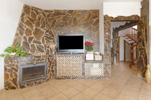 ein Wohnzimmer mit einem TV an einer Steinmauer in der Unterkunft Villa Christisay in Salobre